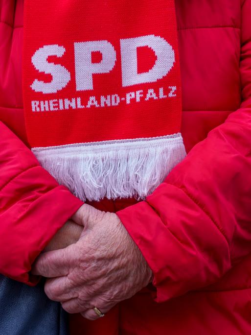 Eine ältere SPD-Anhängerin ist komplett in „Rot“ gekleidet. Sie trägt eine rote Winterjacke und einen Schal mit der Aufschrift "SPD Rheinland-Pfalz".