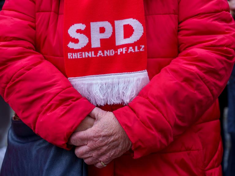 Eine ältere SPD-Anhängerin ist komplett in „Rot“ gekleidet. Sie trägt eine rote Winterjacke und einen Schal mit der Aufschrift "SPD Rheinland-Pfalz".