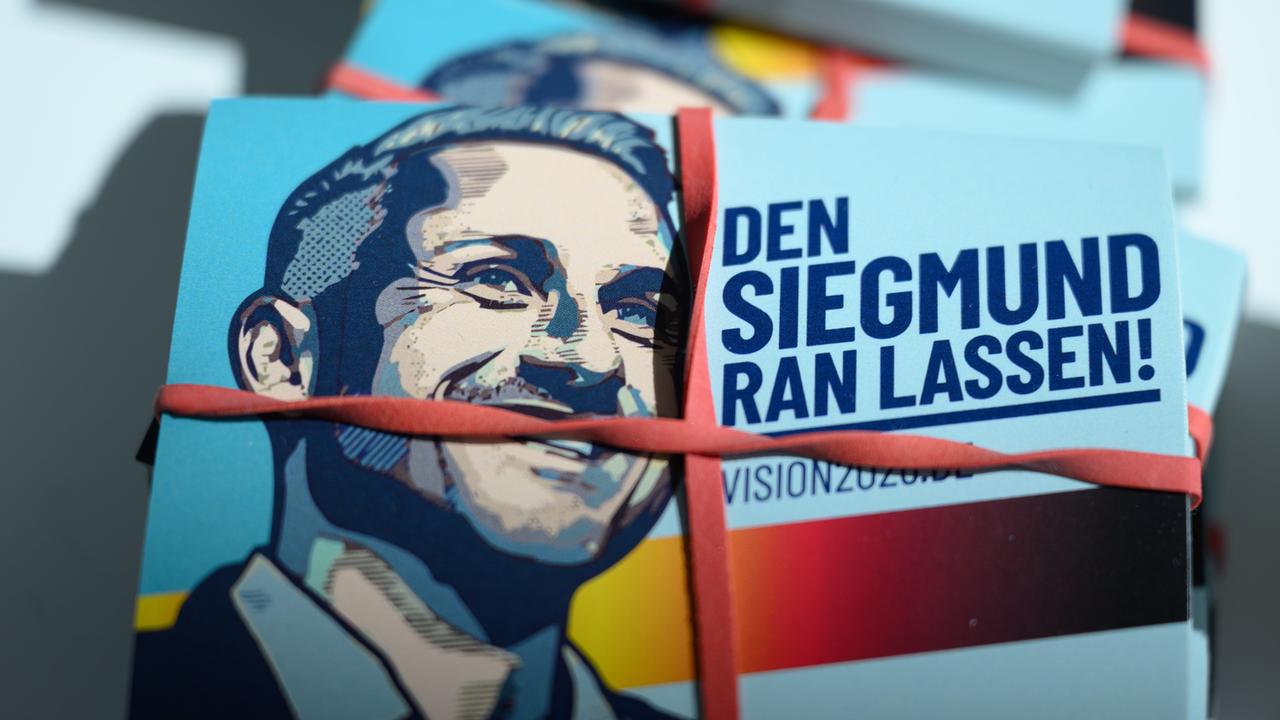 Sticker mit dem Bild von Ulrich Siegmund und der Aufschrift „Den Siegmund ran lassen!“ liegen auf einem Tisch.