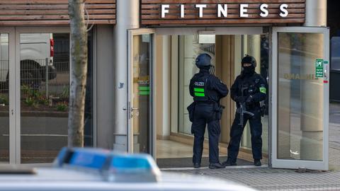 Zu sehen ist der Eingang eines Fitnessstudios in Duisburg. Zwei Polizeibeamte stehen dort nach einer Messerattacke am Eingang.