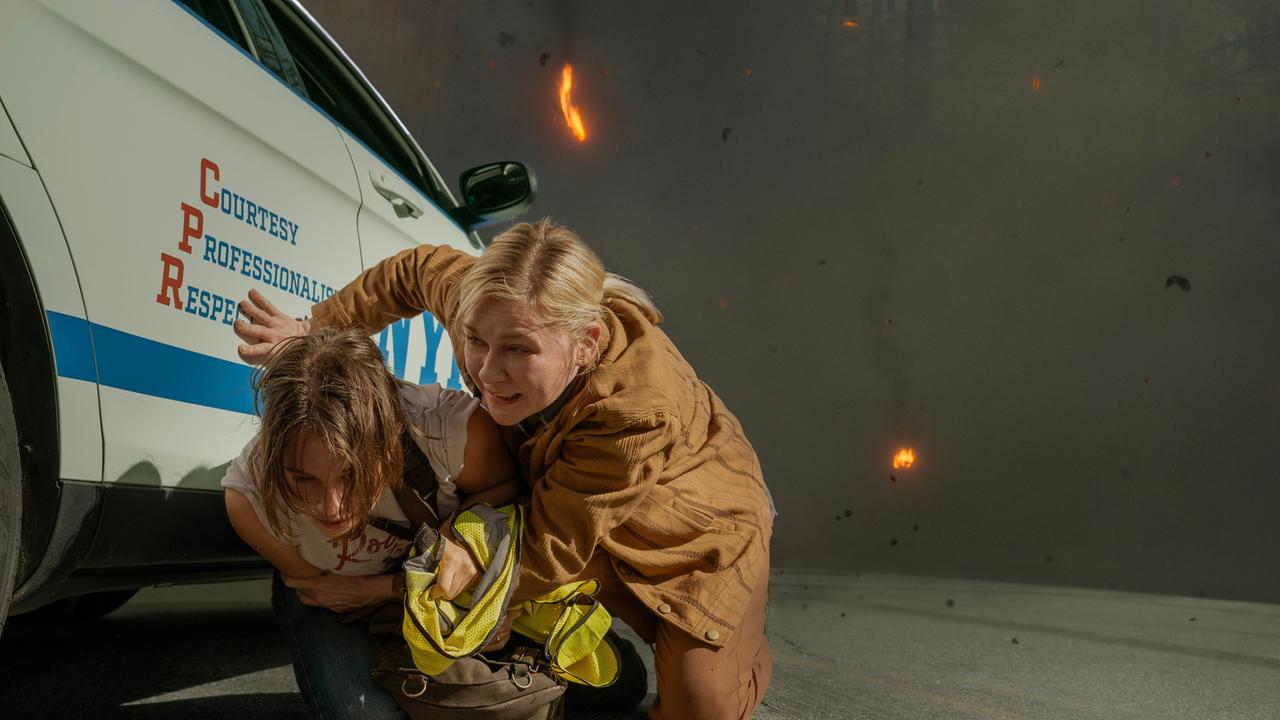 Lee, gespielt von Kirsten Dunst, und Jessie, verkörpert von Cailee Spaeny, ducken sich an der Seite eines Wagens. 