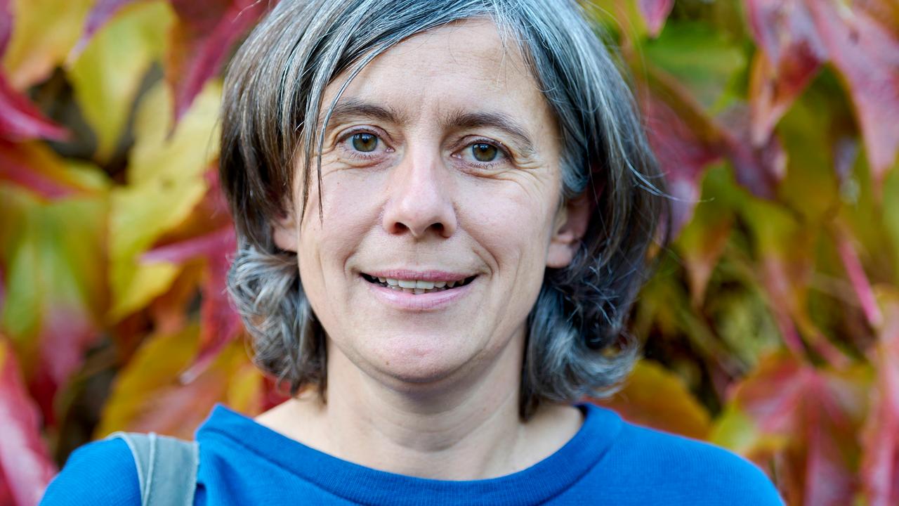 Franziska Tanneberger steht im Freien vor herbstlichem Laub.