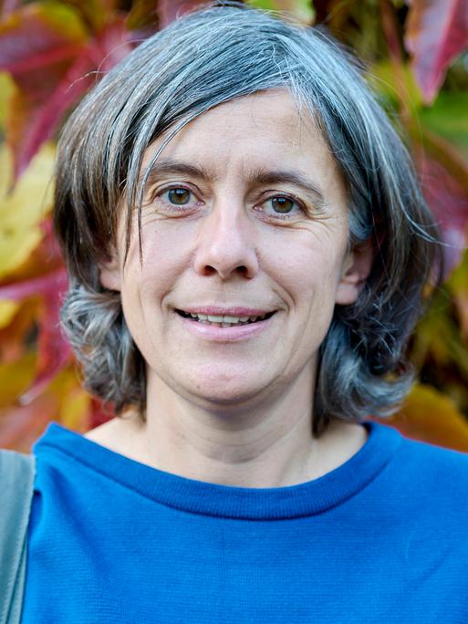 Franziska Tanneberger steht im Freien vor herbstlichem Laub.