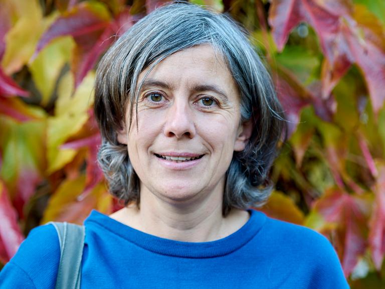 Franziska Tanneberger steht im Freien vor herbstlichem Laub.