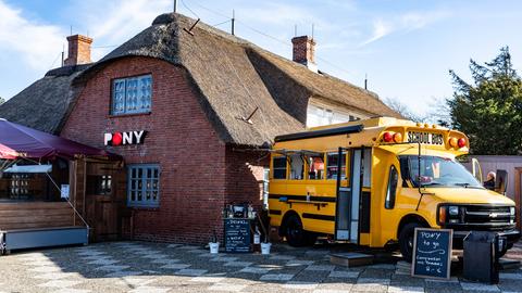 Ein alter amerikanischer Schulbus steht als Ausschank neben dem Lokal Pony in Kampen auf Sylt.