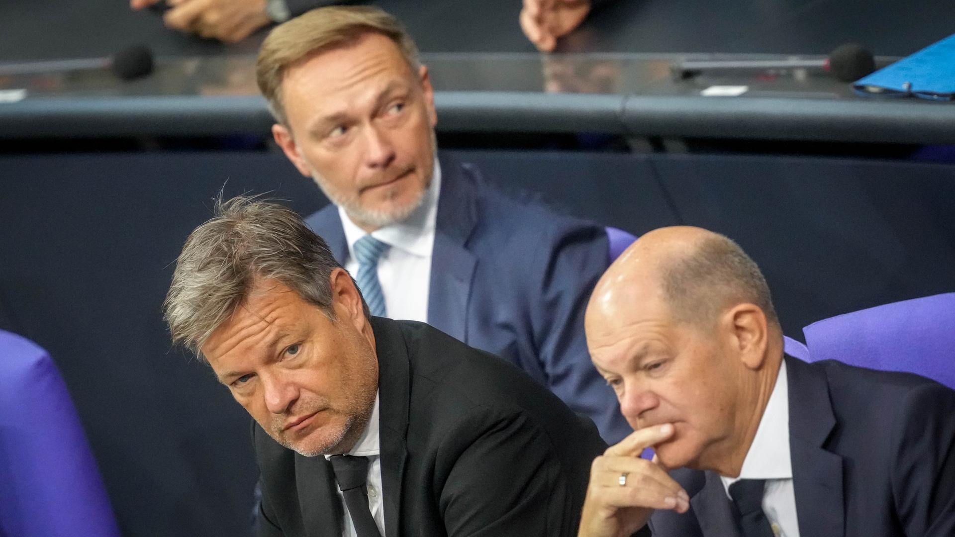 Christian Lindner (M, FDP), Bundesminister der Finanzen, Robert Habeck (l, Bündnis 90/Die Grünen), Bundesminister für Wirtschaft und Klimaschutz, und Bundeskanzler Olaf Scholz (SPD) sitzen auf der Regierungsbank des Bundestags.