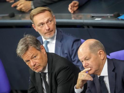 Christian Lindner, Robert Habeck und Olaf Scholz (SPD) sitzen auf der Regierungsbank des Bundestags. Sie blicken in unterschiedliche Richtungen.