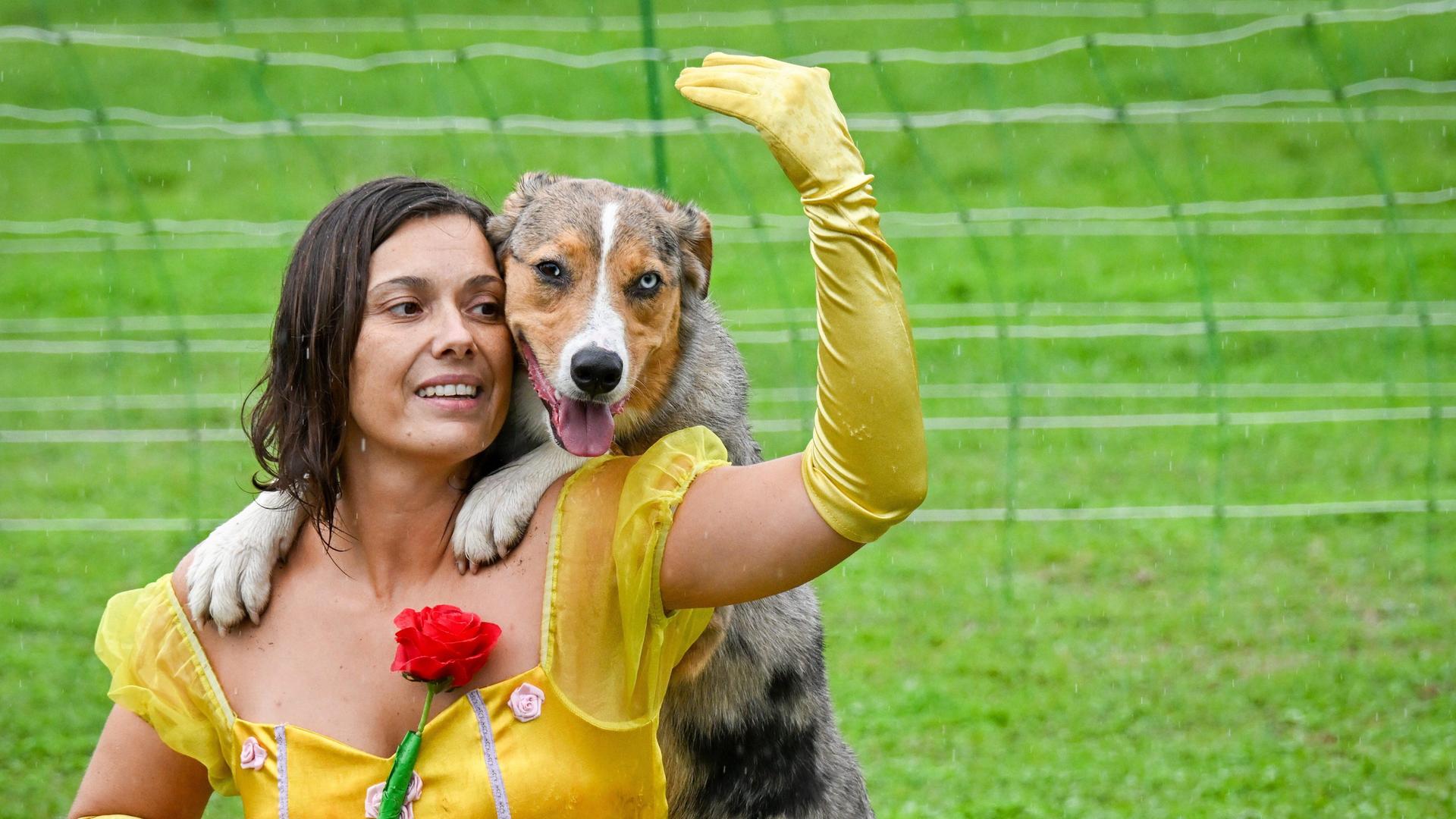 Meisterschaft im Dog Dancing: Eine Frau im Kleid hockt auf dem Boden und hält eine Rose in der Hand. Ein Hund schaut ihr über die Schulter