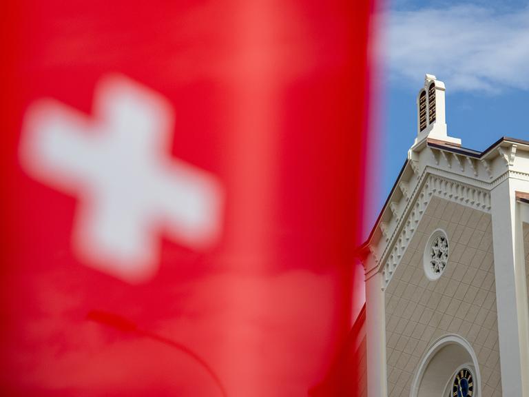 Im Hintergrund eine Synagoge, im Vordergrund die Schweizer Flagge.