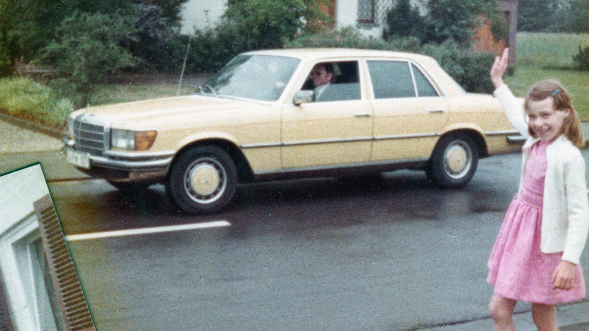 Farbige historische Filmaufnahme eines Mädchens im rosa Kleid was einem Mann in einem gelben Mercedes winkt.