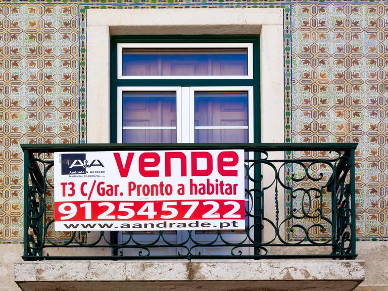 Ein Schild hängt an einem Balkon in Lissabon und macht auf den Immobilienverkauf aufmerksam.