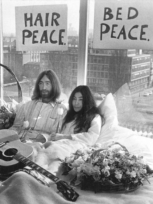 Der Musiker John Lennon von den Beatles und seine Frau Yoko Ono sitzen gemeinsam im Bett während der berühmten „Love-in“-Pressekonferenz in Amsterdam am 25.03.1969.