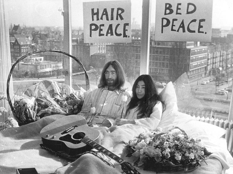 Der Musiker John Lennon von den Beatles und seine Frau Yoko Ono sitzen gemeinsam im Bett während der berühmten „Love-in“-Pressekonferenz in Amsterdam am 25.03.1969.