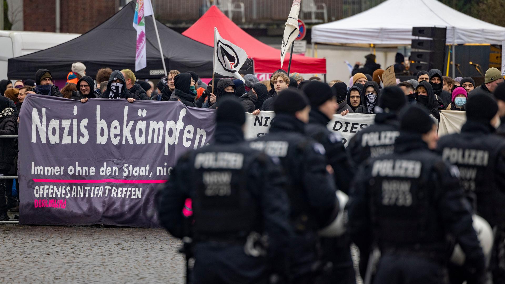 Demonstration gegen den Neujahrsempfang der AfD in Duisburg. Menschen halten ein Banner mit der Aufschrift "Nazis bekämpfen". Im Vordergrund stehen Polizisten. Demonstration gegen den Neujahrsempfang der AfD in Duisburg. Menschen halten ein Banner mit der Aufschrift "Nazis bekämpfen". Im Vordergrund stehen Polizisten.