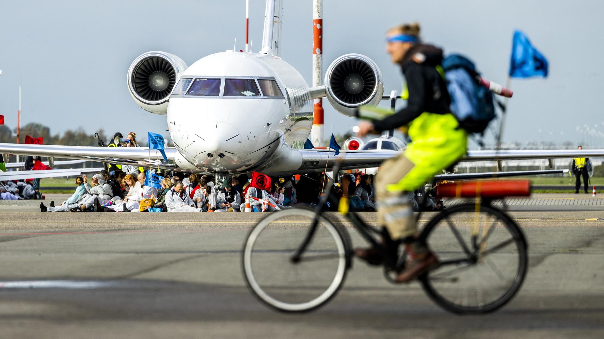 Ein Fahrradfahrer vor einem von Aktivisten blockierten Flugzeug.