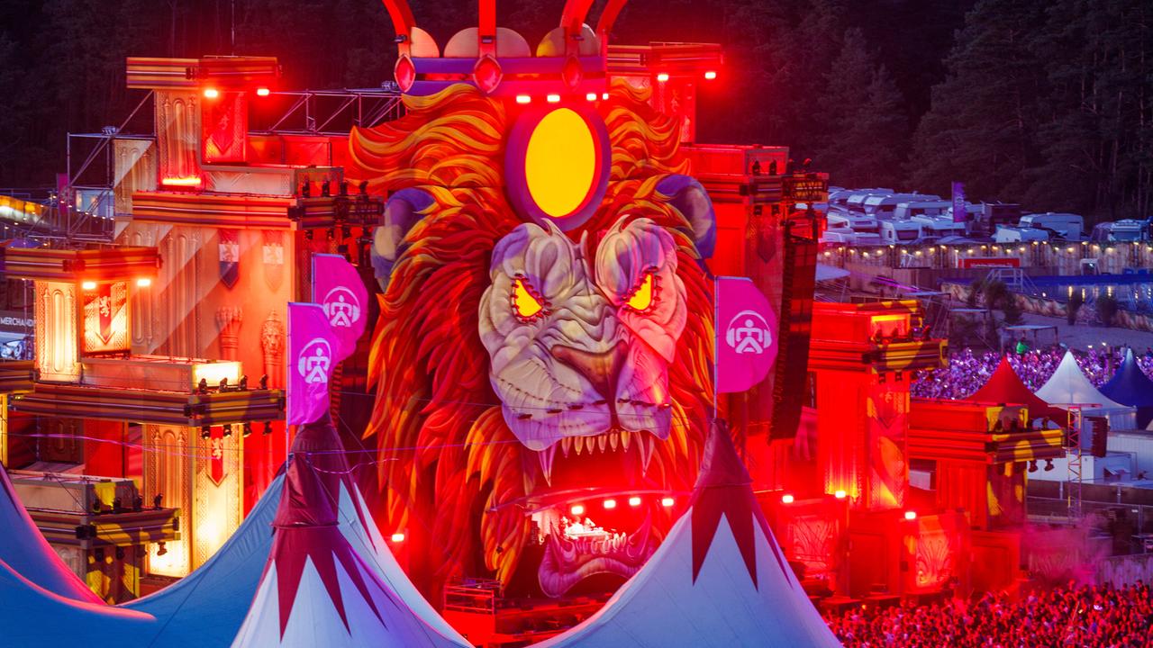 Musikfans tanzen und feiern nach Sonnenuntergang vor einer der Bühnen des "Airbeat One"-Festivals in Mecklenburg-Vorpommern. Die Bühne kommt als großer Löwenkopf daher.