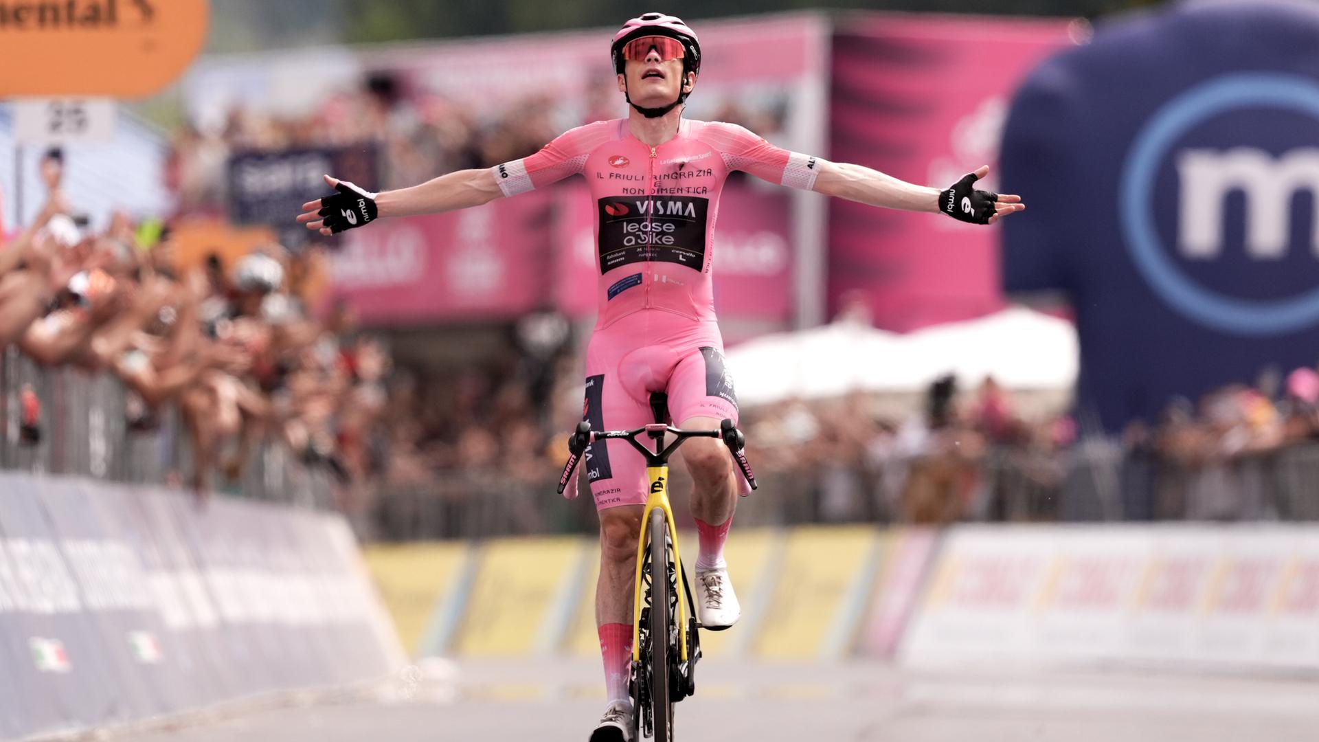 Radprofi Jonas Vingegaard jubelt im Rosa Trikot des Gesamtführenden bei einem Etappensieg.