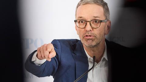 Herbert Kickl spricht auf einer Pressekonferenz und deutet mit seiner rechten Hand nach vorne.