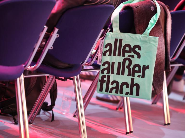 Ein Stoffbeutel mit dem Schriftzug "Alles außer flach" hängt an einem Stuhl auf der Leipziger Buchmesse. 