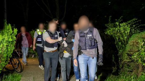 Einsatzkräfte der Polizei führen einen Tatverdächtigen nach seiner Festnahme ab. 