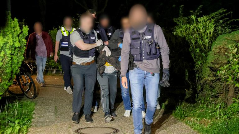 Einsatzkräfte der Polizei führen einen Tatverdächtigen nach seiner Festnahme ab. Einsatzkräfte der Polizei führen einen Tatverdächtigen nach seiner Festnahme ab.