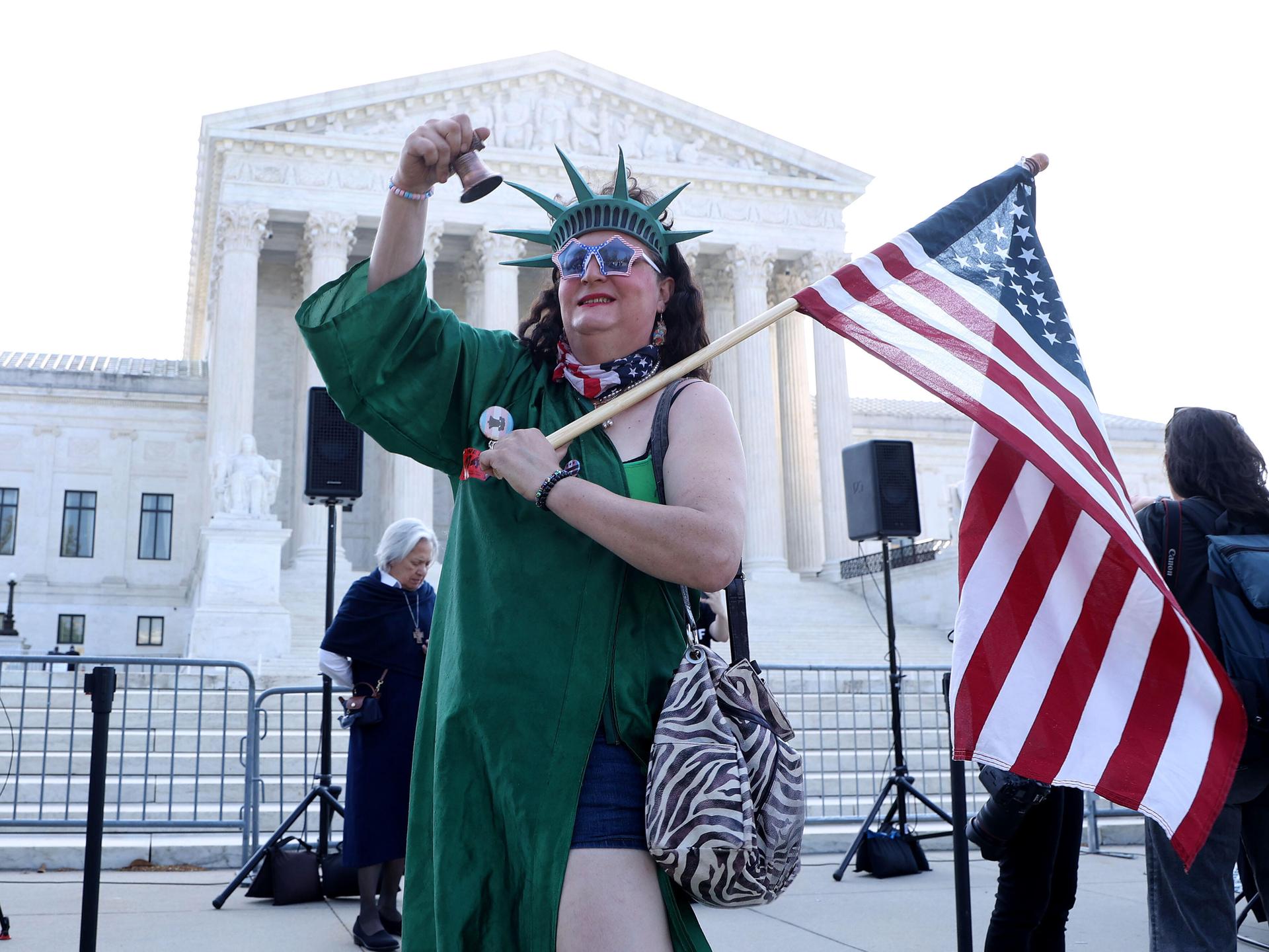Eine als Freiheitsstatue verkleidete Person läutet eine Glocke während einer Kundgebung zur Unterstützung des Geburtsortsprinzips vor dem Obersten Gerichtshof der USA.