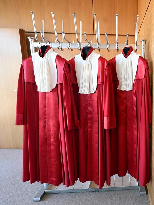 Die roten Roben der Bundesverfassungsrichter hängen in einer Garderobe nebeneinander an Haken. Die roten Roben der Bundesverfassungsrichter hängen in einer Garderobe nebeneinander an Haken.