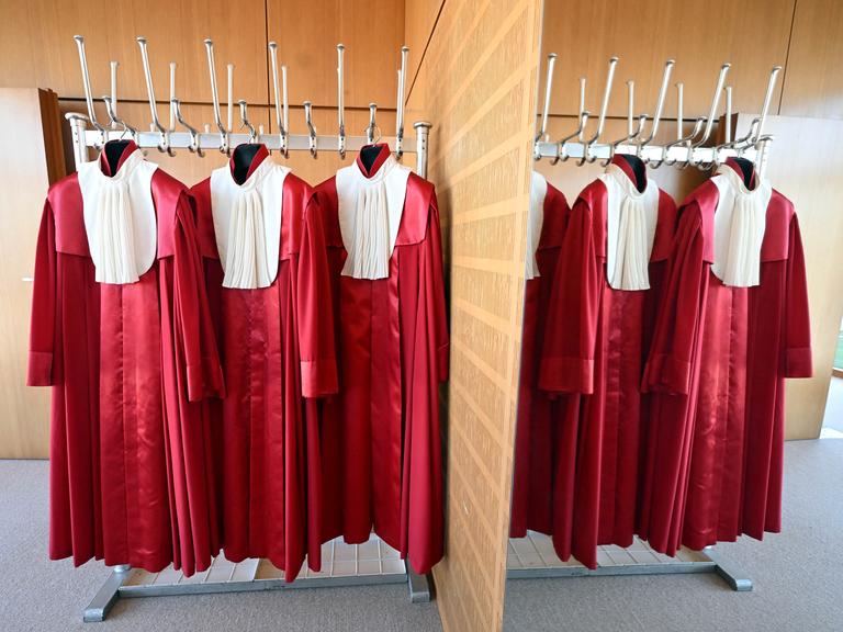 Die roten Roben der Bundesverfassungsrichter hängen in einer Garderobe nebeneinander an Haken. Die roten Roben der Bundesverfassungsrichter hängen in einer Garderobe nebeneinander an Haken.