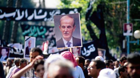 Plakat von Hafiz Al-Assad wird über dem Trauerzug hochgehalten. Tausende Syrer, freiwillig oder delegiert, nehmen am 13.06.2000 an einem Trauermarsch für den am 10. Juni verstorbenen Präsidenten Hafiz Al-Assad teil. Foto: Matthias Tödt