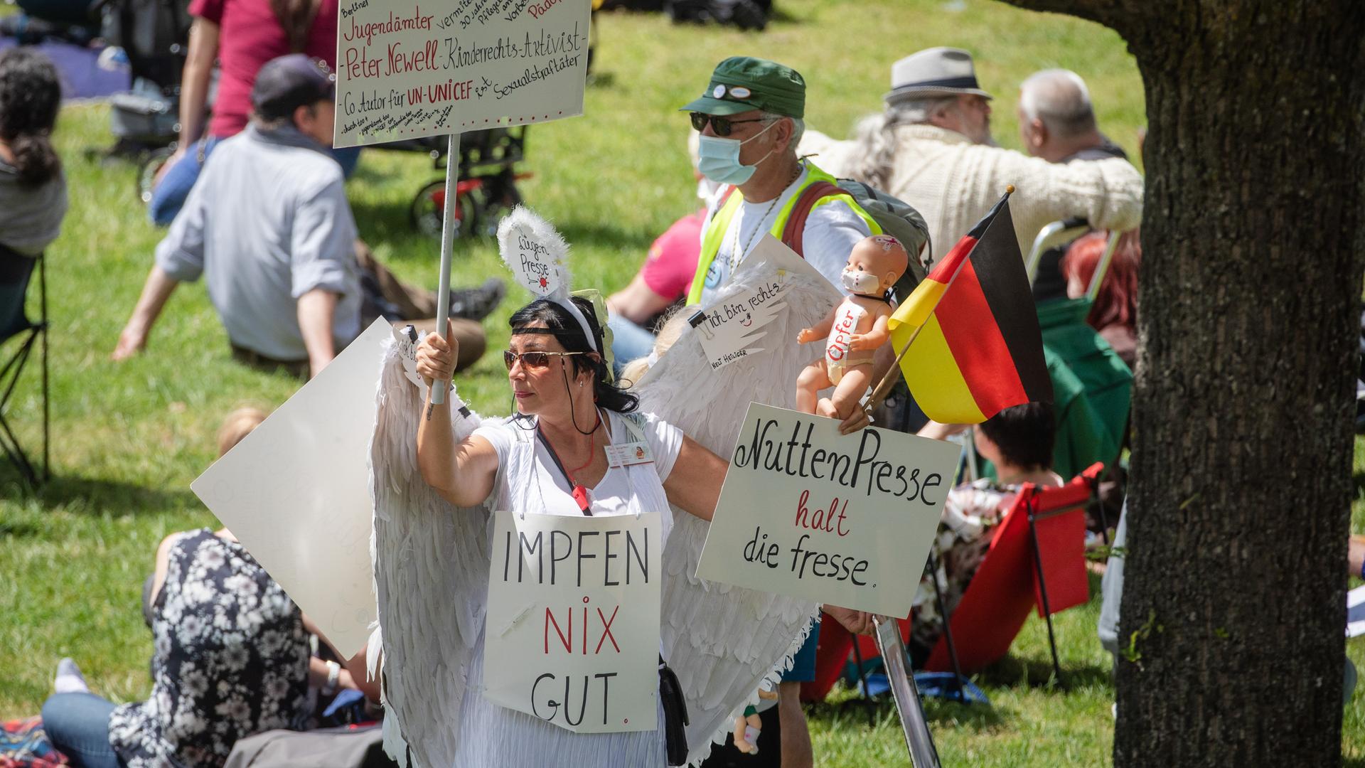 Eine Frau hält auf einer "Querdenker"-Demonstration Schilder, auf denen " Impfen nix gut" und "NuttenPresse halt die Fresse" steht.