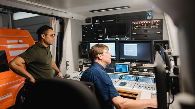 Zwei Techniker vor Monitoren in einem Ü-Wagen von Deutschlandfunk Kultur