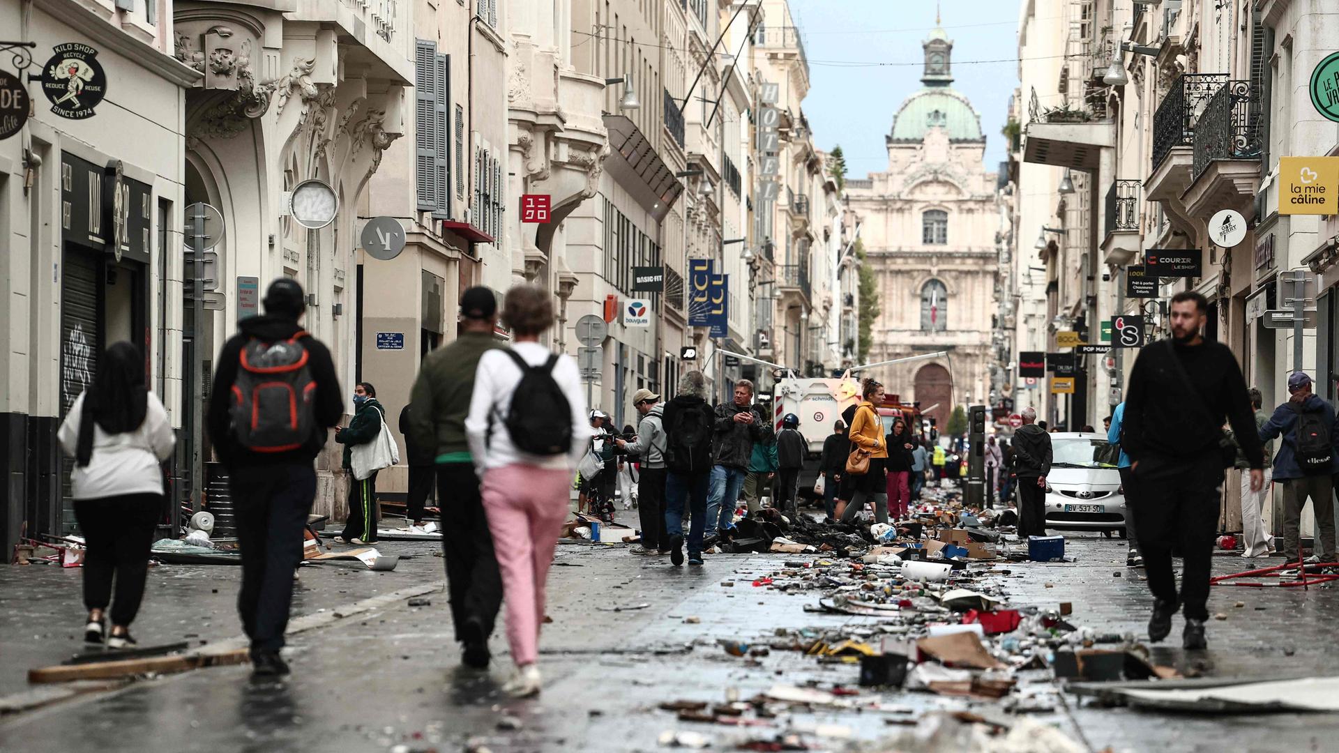Frankreich, Marseille: Fußgänger gehen einen mit Trümmern übersäten Straßenabschnitt entlang, einen Tag nach landesweiten Protesten gegen die hohen Lebenshaltungskosten. 