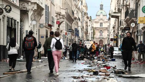 Frankreich, Marseille: Fußgänger gehen einen mit Trümmern übersäten Straßenabschnitt entlang.