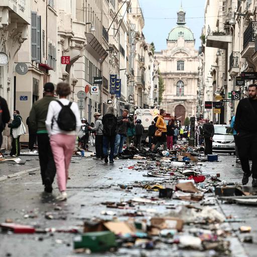 Frankreich, Marseille: Fußgänger gehen einen mit Trümmern übersäten Straßenabschnitt entlang, einen Tag nach landesweiten Protesten gegen die hohen Lebenshaltungskosten. 