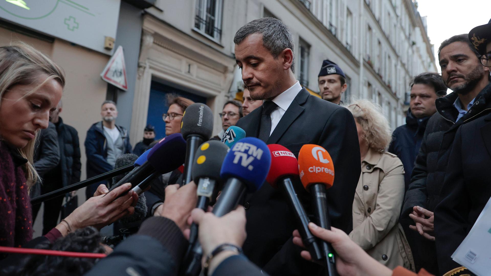 Der französische Innenminister Darmanin spricht mit Reportern auf einer Straße.