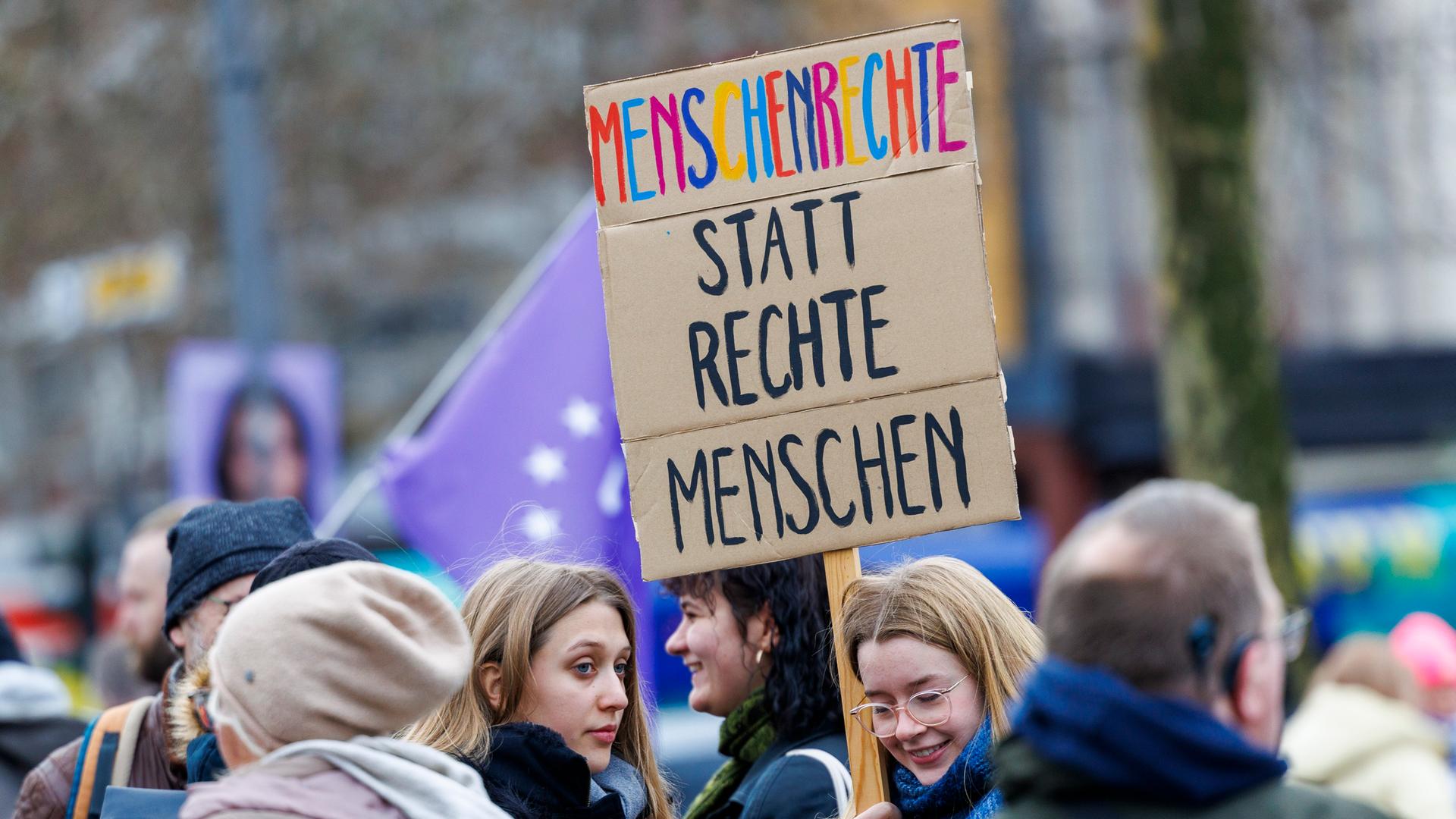 Teilnehmer der Demonstration "5vor 12 - Laut für Demokratie" halten ein Schild mit der Aufschrift "Menschenrechte statt rechte Menschen". 