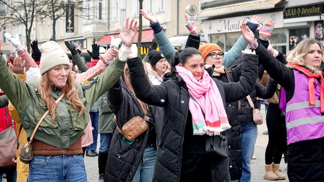 Frauen tanzen auf der One Billion Rising -Aktion vor dem City Center auf der Bahnhofstraße in Herne gegen Gewalt an Frauen und Mädchen. Auf dem Bild sind drei Frauen mit erhobenen Armen im Vordergrund. 