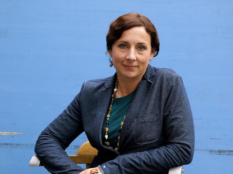 Juli Zeh in blauer Jacke lächelt in die Kamera. Juli Zeh in blauer Jacke lächelt in die Kamera.