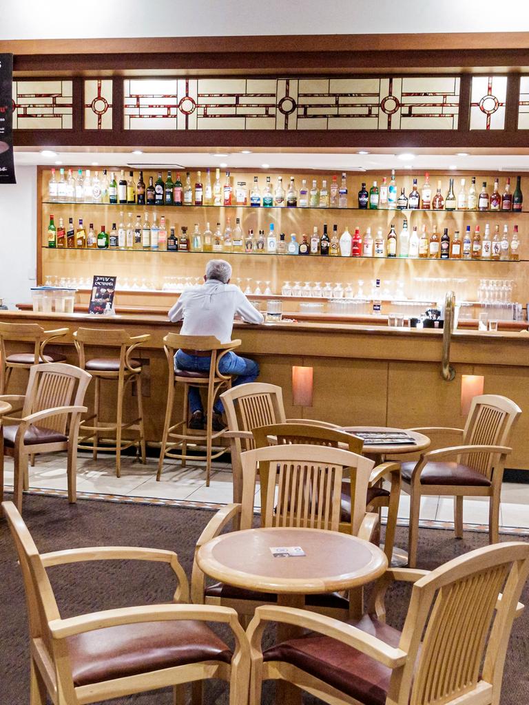 Ein Mann sitzt allein an der Bar eines Restaurants, er ist nur von hinten zu sehen.