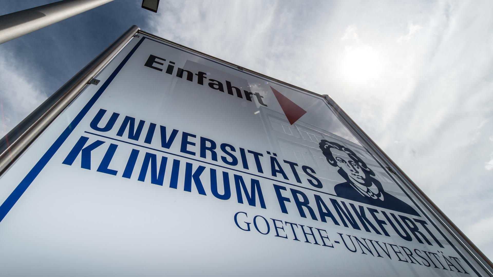 Ein Schild weist auf die Einfahrt zum Universitätsklinikum in Frankfurt am Main hin.
