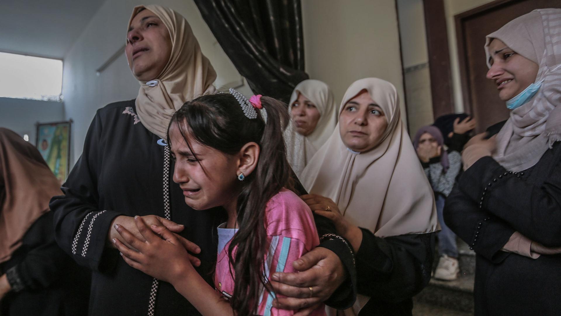 Angehörige trauern während einer Bestattungszeremonie eines bei einem israelischen Luftangriff getöteten Palästinensers. Zu sehen ist ein weinendes Mädchen und mehrere Frauen um sie herum.