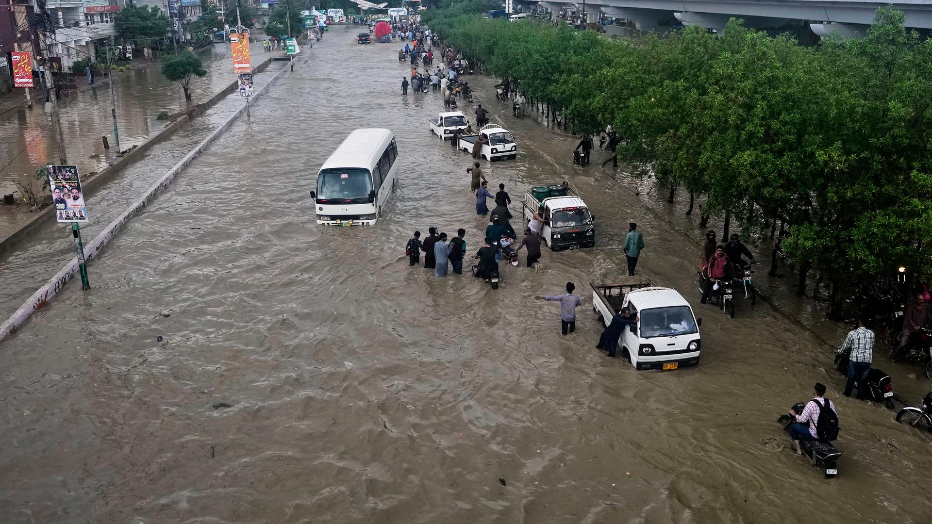 Karachi: Autofahrer schieben ihre Fahrzeuge durch eine überflutete Straße nach starken Regenfällen.