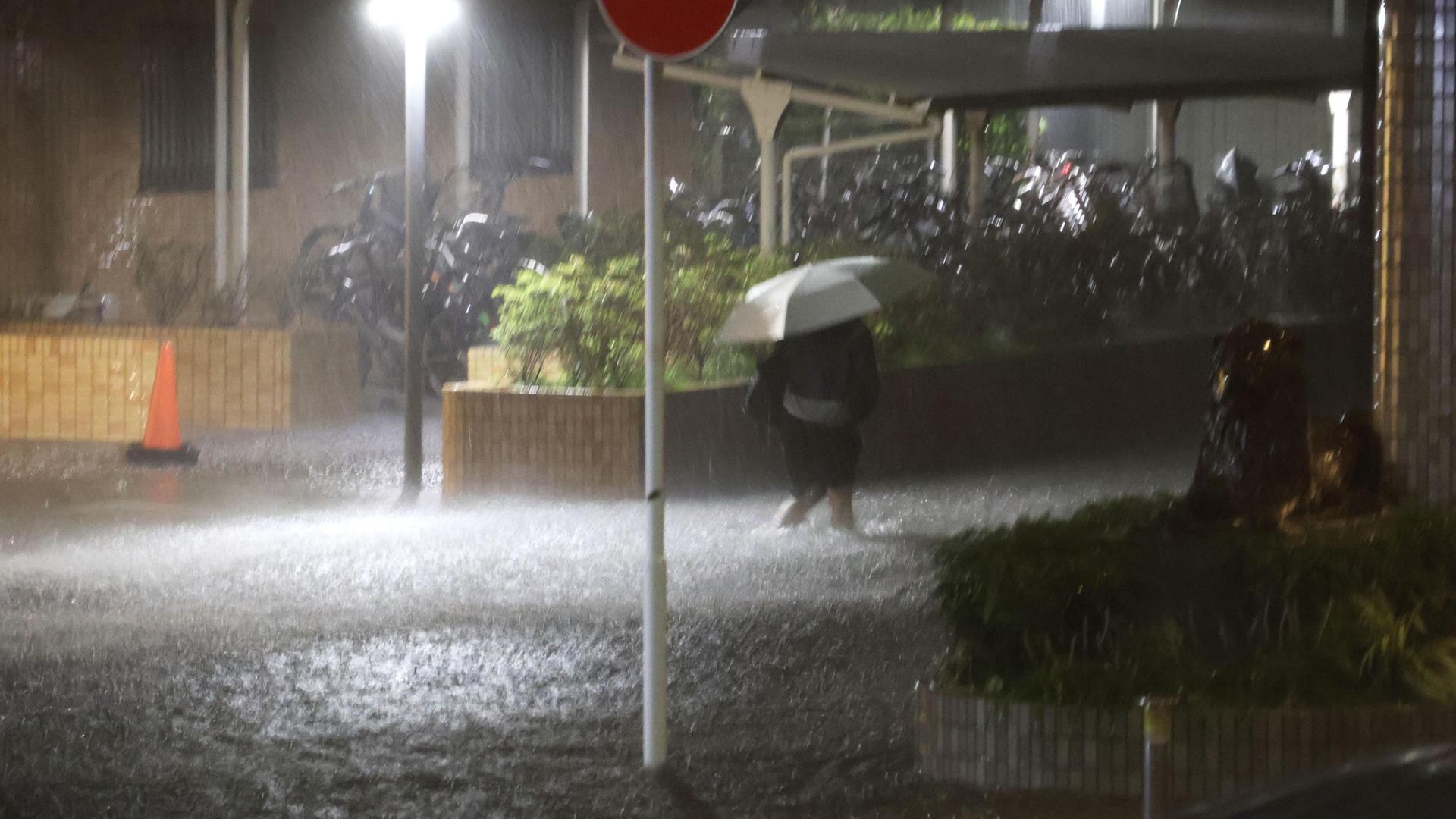 Japan, Chiba: Ein Fußgänger geht auf einer überfluteten Straße in der Stadt Chiba nahe Tokio, nachdem sintflutartige Regenfälle über Ostjapan niedergegangen waren. Japan, Chiba: Ein Fußgänger geht auf einer überfluteten Straße in der Stadt Chiba nahe Tokio, nachdem sintflutartige Regenfälle über Ostjapan niedergegangen waren.