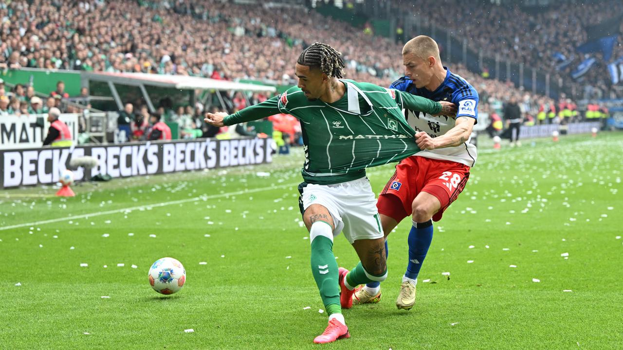 Der Zweikampf ereignet sich nahe der Seitenlinie. Muheim zerrt am grünen Trikot von Njinmah, beide blicken auf den Ball neben ihnen. Im Hintergrund eine vollbesetzte Zuschauertribüne