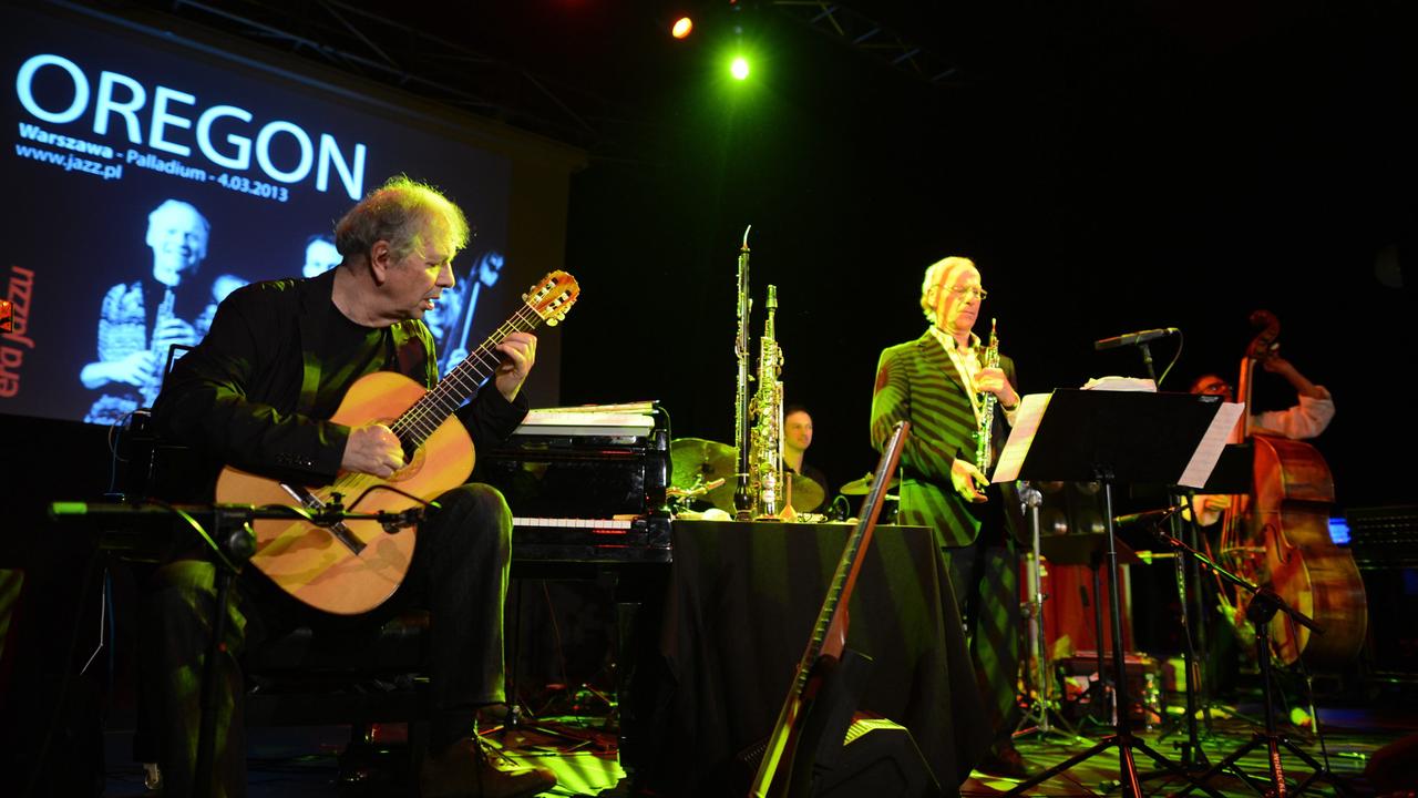 Ralph Towner (Gitarre, Klavier, Synthesizer, Trompete) steht ganz links während eines Konzerts in Warschau auf der Bühne, rechts die anderen Mitglieder der Band "Oregon".