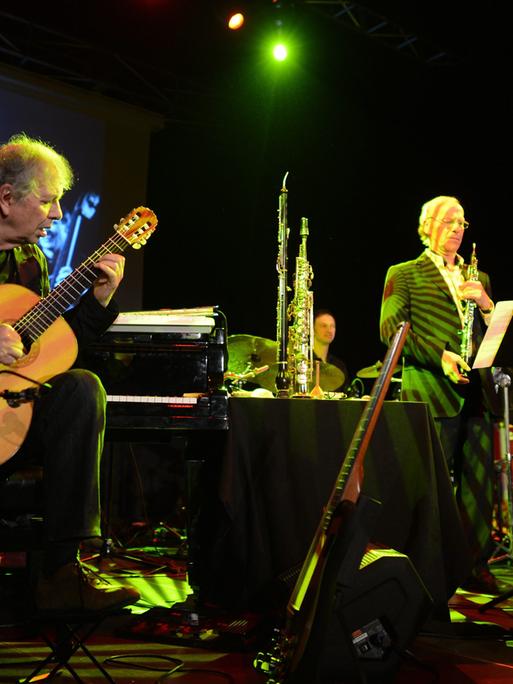 Ralph Towner (Gitarre, Klavier, Synthesizer, Trompete) steht ganz links während eines Konzerts in Warschau auf der Bühne, rechts die anderen Mitglieder der Band "Oregon".