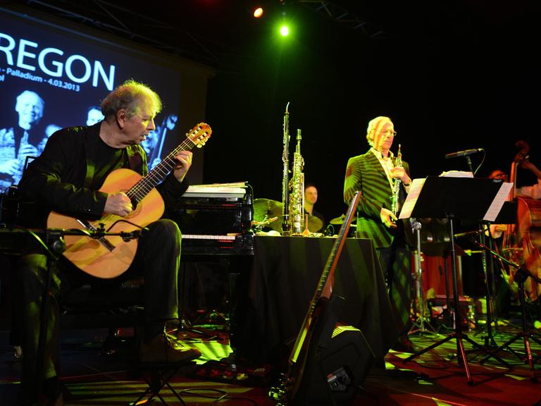 Ralph Towner (Gitarre, Klavier, Synthesizer, Trompete) steht ganz links während eines Konzerts in Warschau auf der Bühne, rechts die anderen Mitglieder der Band "Oregon".