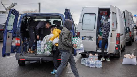 Freiwillige verteilen Wasser an Ukrainische Geflüchtete nach dem Grenzübertritt in Polen. 