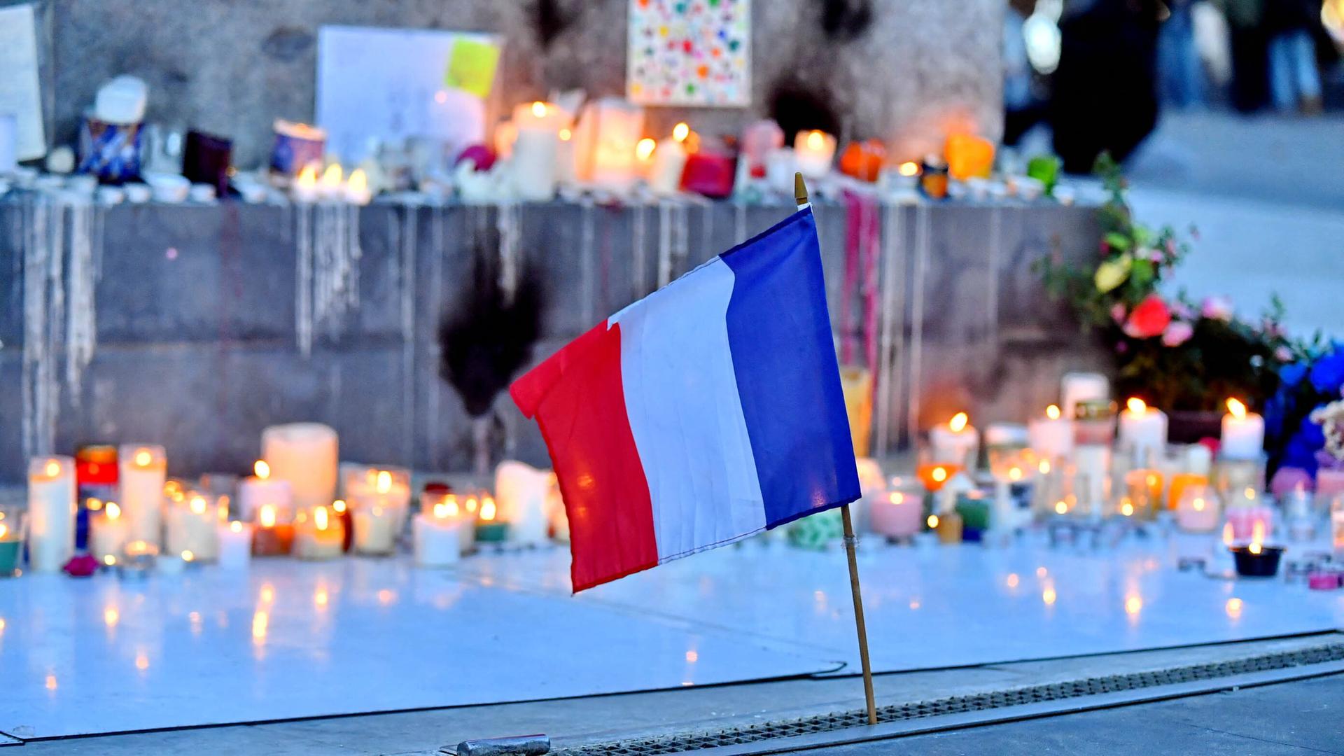 Anlässlich der Anschläge im Bataclan und der Terroranschläge auf die Terrassen der Pariser Cafés werden Kerzen aufgestellt und Blumen niedergelegt auf der Place de la République in Paris. Im Vordergrund ist eine kleine Frankreichfahne zu sehen Anlässlich der Anschläge im Bataclan und der Terroranschläge auf die Terrassen der Pariser Cafés werden Kerzen aufgestellt und Blumen niedergelegt auf der Place de la République in Paris. Im Vordergrund ist eine kleine Frankreichfahne zu sehen