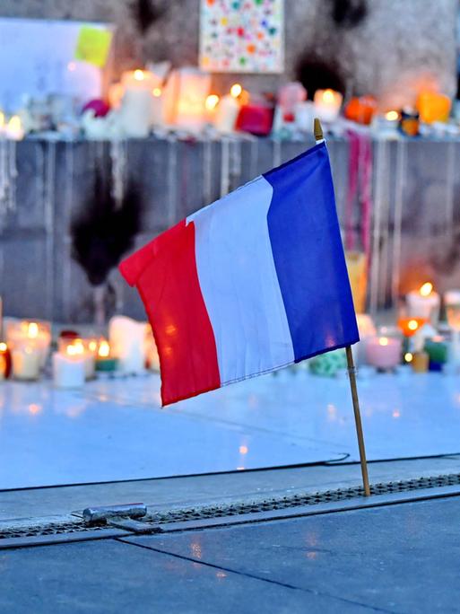 Anlässlich der Anschläge im Bataclan und der Terroranschläge auf die Terrassen der Pariser Cafés werden Kerzen aufgestellt und Blumen niedergelegt auf der Place de la République in Paris. Im Vordergrund ist eine kleine Frankreichfahne zu sehen 